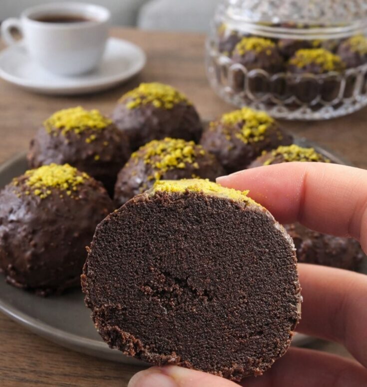 Στρογγυλά σοκολατένια τρουφάκια καλυμμένα με γυαλιστερό γλάσο σοκολάτας, τοποθετημένα επάνω σε λαδόκολλα.