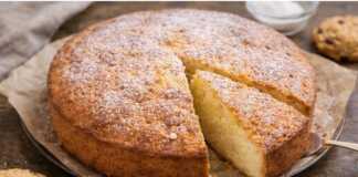 Ένα χρυσαφένιο σιμιγδαλόπαστο κέικ κομμένο σε ρόμβους, πασπαλισμένο ελαφρώς με άχνη ζάχαρη.