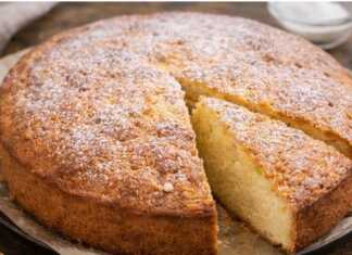 Ένα χρυσαφένιο σιμιγδαλόπαστο κέικ κομμένο σε ρόμβους, πασπαλισμένο ελαφρώς με άχνη ζάχαρη.