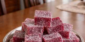 Μικροί κύβοι από χειροποίητα ζελεδάκια βατόμουρου σε έντονο κόκκινο χρώμα, καλυμμένοι με ζάχαρη και τοποθετημένοι σε σειρά.