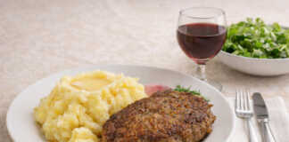 1 ροδοκοκκινισμέναο μπιφτέκια τοποθετημένα δίπλα σε μια πλούσια δόση κρεμώδους πουρέ πατάτας, γαρνιρισμένα με φρέσκο πιπέρι