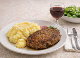 1 ροδοκοκκινισμέναο μπιφτέκια τοποθετημένα δίπλα σε μια πλούσια δόση κρεμώδους πουρέ πατάτας, γαρνιρισμένα με φρέσκο πιπέρι