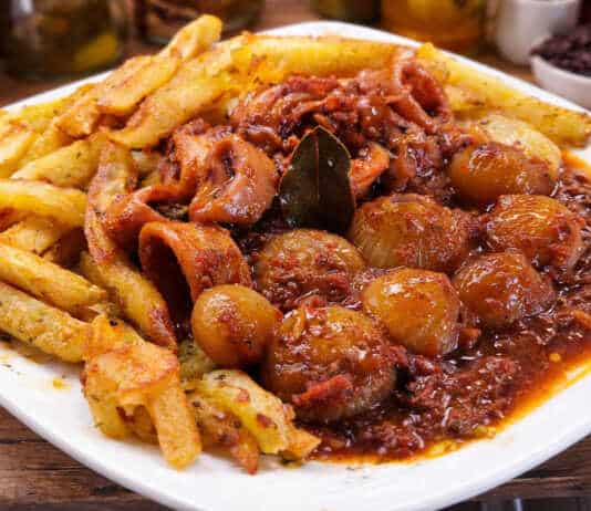 Καλαμαράκια στιφάδο σε πλούσια κόκκινη σάλτσα με κρεμμυδάκια κοκάρι δίπλα σε χρυσαφένιες τηγανητές πατάτες