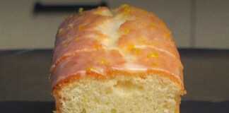 Ένα μακρόστενο κέικ λεμονιού καλυμμένο με λευκό γυαλιστερό γλάσο και λεπτές λωρίδες κίτρινου ξύσματος στην κορυφή