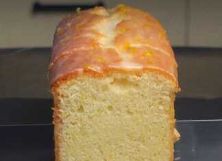 Ένα μακρόστενο κέικ λεμονιού καλυμμένο με λευκό γυαλιστερό γλάσο και λεπτές λωρίδες κίτρινου ξύσματος στην κορυφή