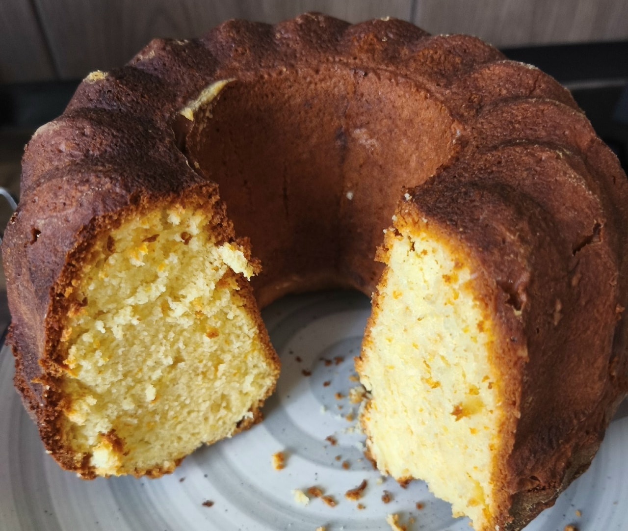 Εντυπωσιακό κέικ Bundt πορτοκαλιού πασπαλισμένο με άχνη ζάχαρη πάνω σε σχάρα ψύξης