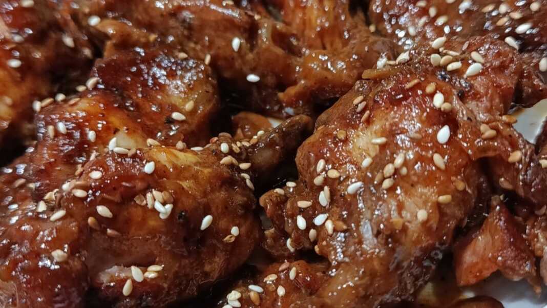καραμελωμένες φτερούγες κοτόπουλου σε σκούρα σάλτσα βαλσάμικου, πασπαλισμένες με μπόλικο καβουρδισμένο σουσάμι
