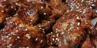 καραμελωμένες φτερούγες κοτόπουλου σε σκούρα σάλτσα βαλσάμικου, πασπαλισμένες με μπόλικο καβουρδισμένο σουσάμι