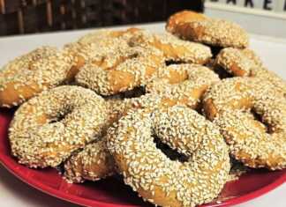 Σειρές από χρυσαφένια νηστίσιμα κουλουράκια καλυμμένα με σουσάμι πάνω σε ταψί με λαδόκολλα