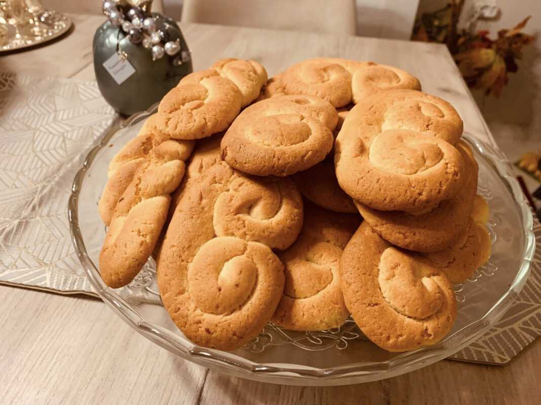 Σειρές από χρυσαφένια κουλουράκια πορτοκαλιού πάνω σε αντικολλητικό χαρτί, αχνιστά και μοσχομυριστά