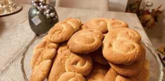 Σειρές από χρυσαφένια κουλουράκια πορτοκαλιού πάνω σε αντικολλητικό χαρτί, αχνιστά και μοσχομυριστά