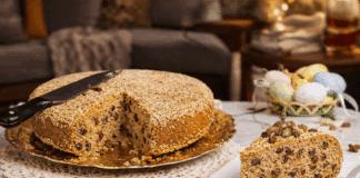 Αφράτη Σταφιδόπιτα με άρωμα τσουρεκιού, πασπαλισμένη με σουσάμι και κομμένη σε ρόμβους πάνω σε ξύλινη επιφάνεια