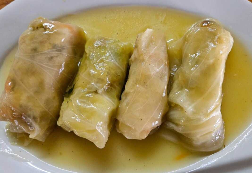 Καλοτυλιγμένοι νηστίσιμοι λαχανοντολμάδες μέσα στην κατσαρόλα, περιχυμένοι με λευκή σάλτσα και πασπαλισμένοι με φρέσκα μυρωδικά