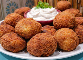 Ροδισμένοι, τραγανοί πατατοκεφτέδες σε πιατέλα, σερβιρισμένοι με ένα μπολάκι λευκή σως γιαουρτιού και φρέσκια ρίγανη