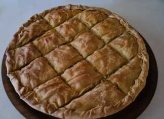 Μια μεγάλη στρογγυλή πρασοκιμαδόπιτα Μακεδονίας με χρυσαφένιο τραγανό φύλλο και πλούσιο κόθρο, κομμένη σε κομμάτια