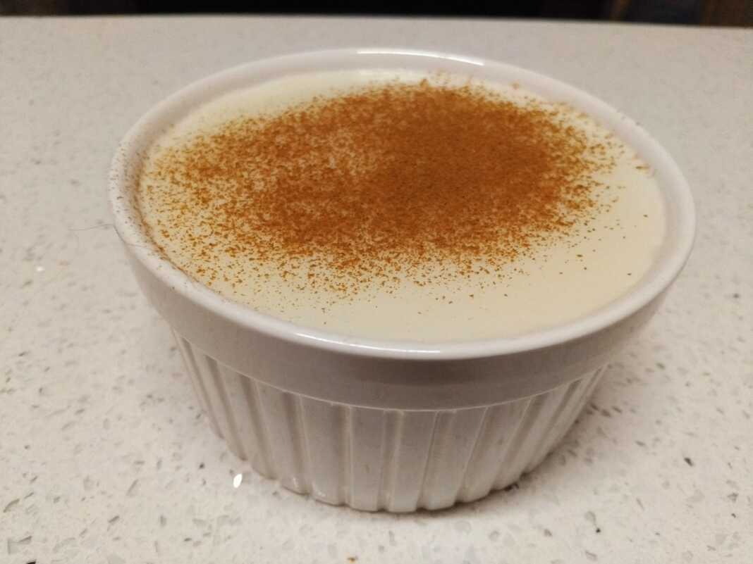 Ένα λευκό μπολ με κρεμώδες ρυζόγαλο πασπαλισμένο με μπόλικη κανέλα στην κορυφή