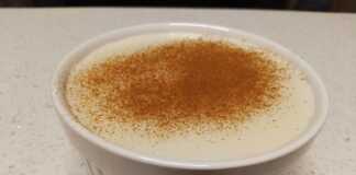 Ένα λευκό μπολ με κρεμώδες ρυζόγαλο πασπαλισμένο με μπόλικη κανέλα στην κορυφή