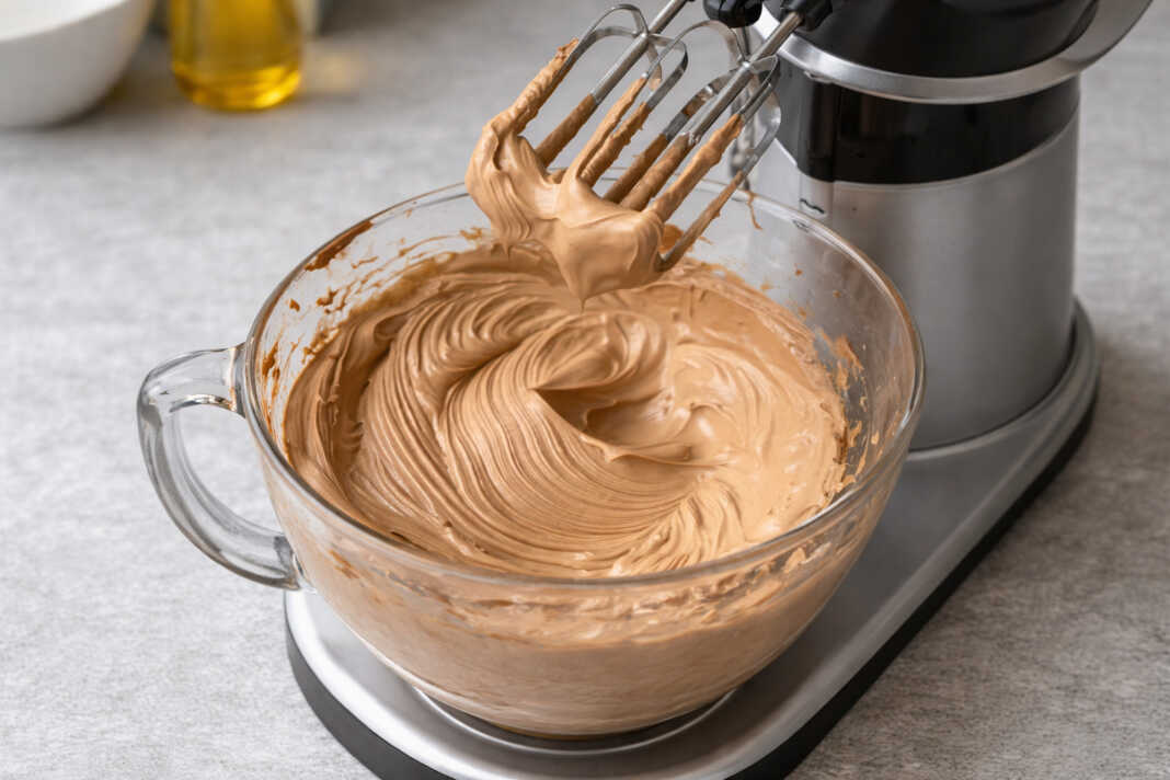 Μια λεία και γυαλιστερή σοκολατένια γκανάς που απλώνεται ομοιόμορφα πάνω σε μια τούρτα με τη βοήθεια σπάτουλας