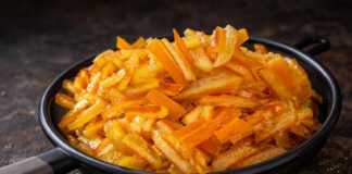 Σιροπιαστά στικς Πορτοκαλιού Χρυσαφένια Σιροπιαστά στικς πορτοκαλιού κομμένα σε λεπτές λωρίδες, πασπαλισμένα με άχνη ζάχαρη πάνω σε λαδόκολλα