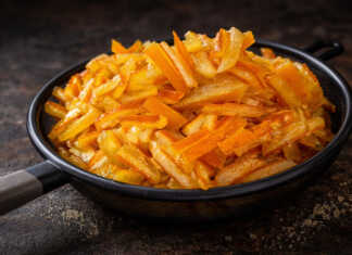 Χρυσαφένια Σιροπιαστά στικς πορτοκαλιού κομμένα σε λεπτές λωρίδες, πασπαλισμένα με άχνη ζάχαρη πάνω σε λαδόκολλα