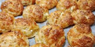 Μικρά ροδοκοκκινισμένα τυροπιτάκια πασπαλισμένα με σουσάμι πάνω σε λαδόκολλα, φρεσκοψημένα και αχνιστά