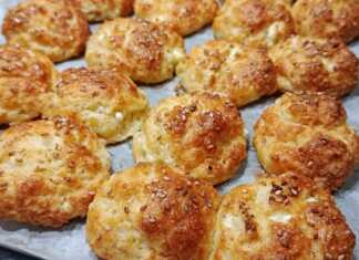 Μικρά ροδοκοκκινισμένα τυροπιτάκια πασπαλισμένα με σουσάμι πάνω σε λαδόκολλα, φρεσκοψημένα και αχνιστά