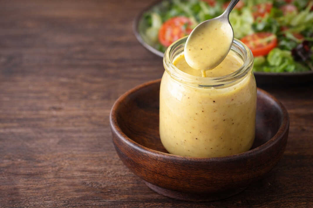 Κρεμώδης σάλτσα honey mustard σε μικρό μπολ δίπλα σε τραγανή σαλατα
