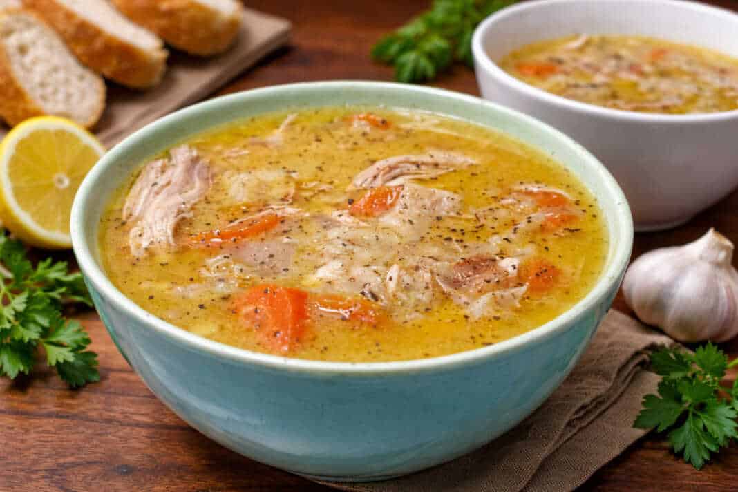 Μπολ με αχνιστή κοτόσουπα αυγολέμονο, κομμάτια από τρυφερό κοτόπουλο, καρότα και κριθαράκι, γαρνιρισμένο με φρεσκοτριμμένο πιπέρι