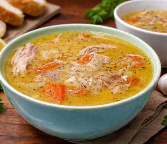 Μπολ με αχνιστή κοτόσουπα αυγολέμονο, κομμάτια από τρυφερό κοτόπουλο, καρότα και κριθαράκι, γαρνιρισμένο με φρεσκοτριμμένο πιπέρι