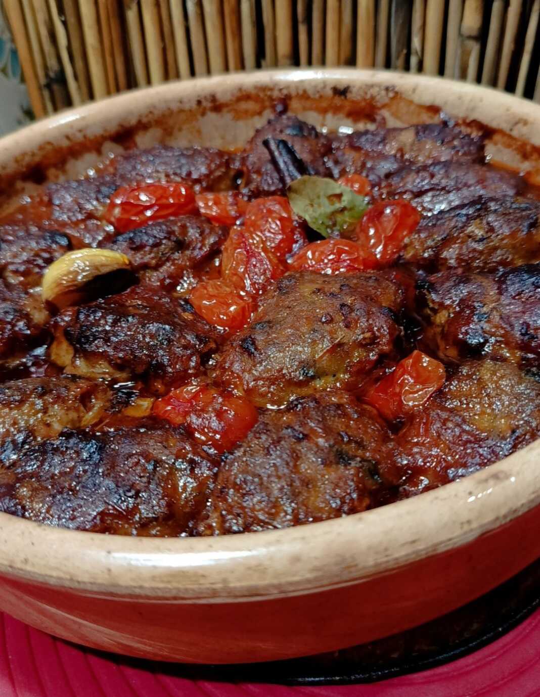 Ταψάκι με ροδοκοκκινισμένα κεφτεδάκια, φρέσκα ψημένα ντοματίνια και πλούσια κόκκινη σάλτσα.