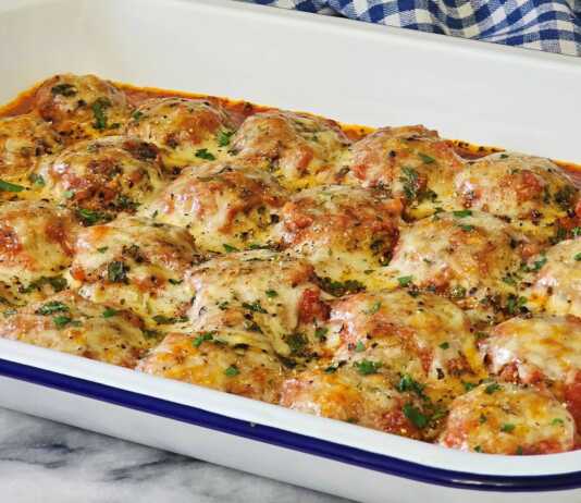 Ζουμερά ιταλικά κεφτεδάκια μέσα σε πλούσια σάλτσα ντομάτας, καλυμμένα με λιωμένη μοτσαρέλα και παρμεζάνα, σε ένα πυρίμαχο σκεύος.