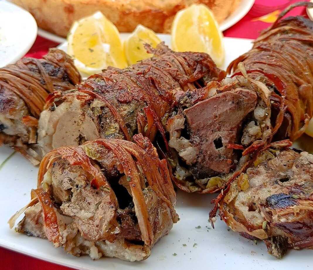 Παραδοσιακό κοκορέτσι στη σούβλα, τυλιγμένο σφιχτά με έντερα και σκέπη, να ροδίζει πάνω από τα κάρβουνα αλειμμένο με λαδολέμονο.