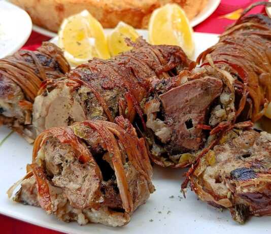 Παραδοσιακό κοκορέτσι στη σούβλα, τυλιγμένο σφιχτά με έντερα και σκέπη, να ροδίζει πάνω από τα κάρβουνα αλειμμένο με λαδολέμονο.