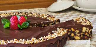 Ένα εντυπωσιακό σοκολατένιο γλυκό ψυγείου σε στρογγυλή φόρμα, καλυμμένο με γυαλιστερή γκανάζ σοκολάτας και διακοσμημένο με ολόκληρα καβουρδισμένα φουντούκια.