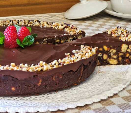 Ένα εντυπωσιακό σοκολατένιο γλυκό ψυγείου σε στρογγυλή φόρμα, καλυμμένο με γυαλιστερή γκανάζ σοκολάτας και διακοσμημένο με ολόκληρα καβουρδισμένα φουντούκια.