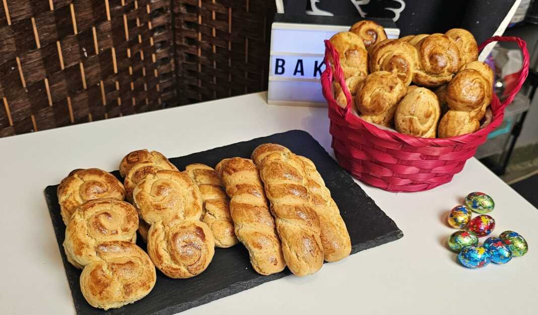 Σειρές από χρυσαφένια πλεγμένα πασχαλινά κουλουράκια αμμωνίας πάνω σε λαδόκολλα, γυαλιστερά από το άλειμμα αυγού