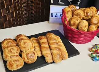 Σειρές από χρυσαφένια πλεγμένα πασχαλινά κουλουράκια αμμωνίας πάνω σε λαδόκολλα, γυαλιστερά από το άλειμμα αυγού