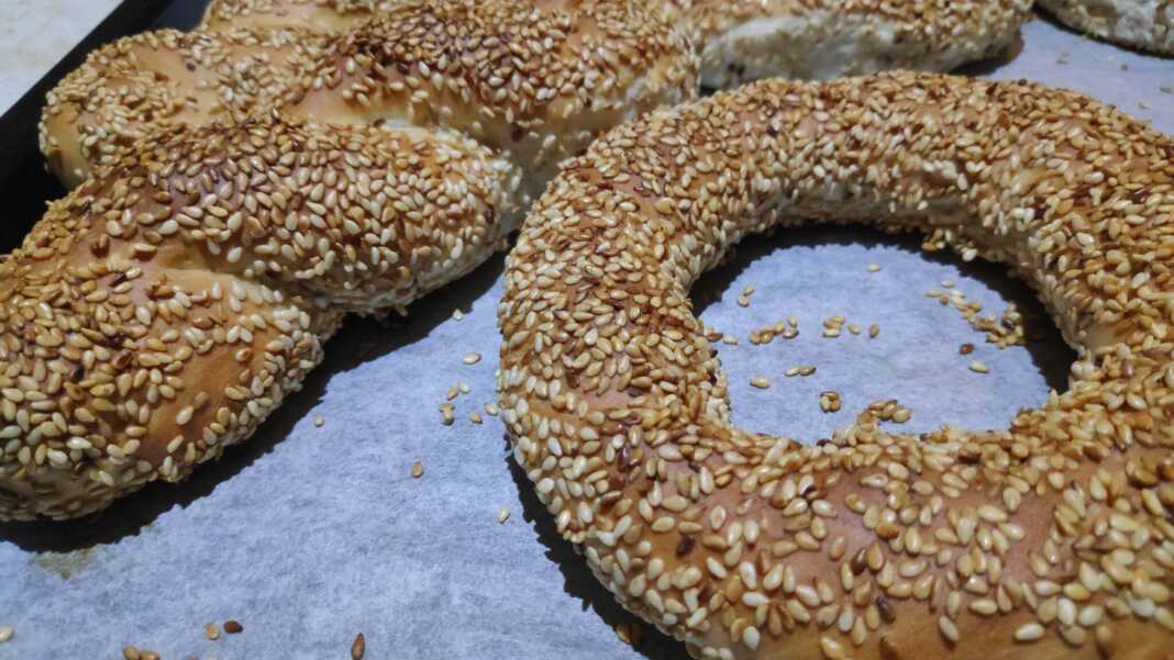 Φρεσκοψημένα κουλούρια Θεσσαλονίκης γεμάτα σουσάμι πάνω σε αντικολλητικό χαρτί, με χρυσαφένια όψη και παραδοσιακό σχήμα κρίκου και κοτσιδα