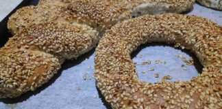 Φρεσκοψημένα κουλούρια Θεσσαλονίκης γεμάτα σουσάμι πάνω σε αντικολλητικό χαρτί, με χρυσαφένια όψη και παραδοσιακό σχήμα κρίκου και κοτσιδα