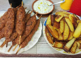 Ροδοκοκκινισμένα λουλά κεμπάπ σε ξυλάκια μέσα στο καλάθι του air fryer, σερβιρισμένα με δροσερό τζατζίκι.