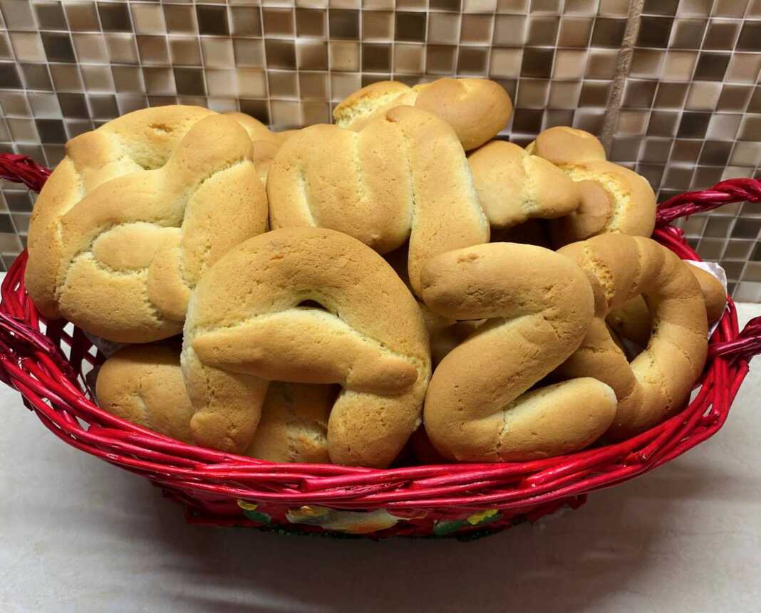 Δίσκος με καλοσχηματισμένα πασχαλινά κουλουράκια, λαμπερά από το άλειμμα αυγού, τοποθετημένα δίπλα σε πασχαλινά αυγά