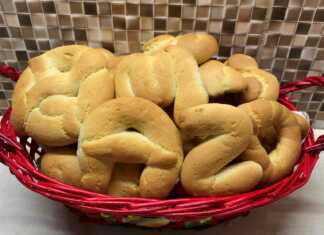 Δίσκος με καλοσχηματισμένα πασχαλινά κουλουράκια, λαμπερά από το άλειμμα αυγού, τοποθετημένα δίπλα σε πασχαλινά αυγά