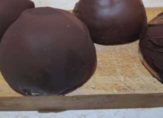 Σειρές από στρογγυλά τρουφάκια καλυμμένα με γυαλιστερή σοκολάτα, τοποθετημένα πάνω σε αντικολλητικό χαρτί.