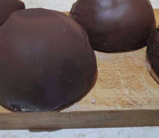 Σειρές από στρογγυλά τρουφάκια καλυμμένα με γυαλιστερή σοκολάτα, τοποθετημένα πάνω σε αντικολλητικό χαρτί.