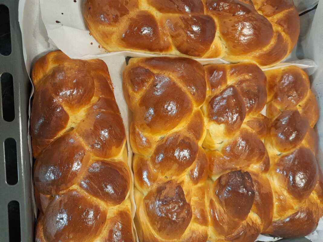 Πέντε καλοσχηματισμένα, γυαλιστερά τσουρέκια πάνω σε αντικολλητικό χαρτί, με έντονο άρωμα μαστίχας και μαχλεπιού