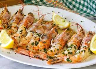 Ζουμερές γαρίδες Αργεντινής ψημένες στο φούρνο, περιχυμένες με σάλτσα ελαιολάδου, λεμονιού και φρέσκου μαϊντανού μέσα σε ένα κεραμικό σκεύος.