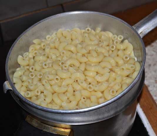 Αχνιστά μακαρόνια μέσα σε κατσαρόλα, ανακατεμένα με λιωμένο βούτυρο και τη γυαλιστερή σάλτσα από το νερό τους.