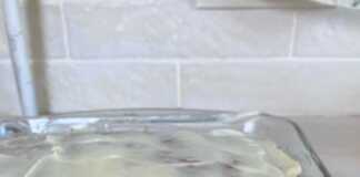 Αφράτο ορθογώνιο κέικ καρότου με λευκή επικάλυψη κρέμας τυριού, κομμένο σε τετράγωνα κομμάτια και διακοσμημένο με ψιλοκομμένα καρύδια στην κορυφή