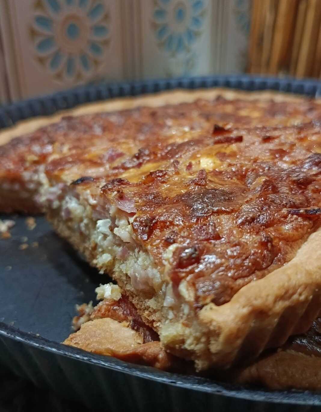 kis loren me mpeikon Ροδοψημένη, λαχταριστή και αφράτη κις λορέν με μπέικον και λιωμένα τυριά, κομμένη σε κομμάτια μέσα στην ταρτιέρα της, έτοιμη για σερβίρισμα.