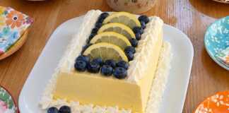 Αυθεντικό ιταλικό lemon semifreddo σερβιρισμένο σε πιατέλα, γαρνιρισμένο με ροζέτες σαντιγί, φρέσκα μύρτιλα και λεπτές ροδέλες λεμονιού